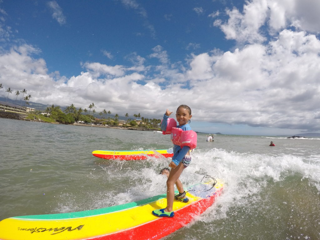 little girl surfing throwing shaka